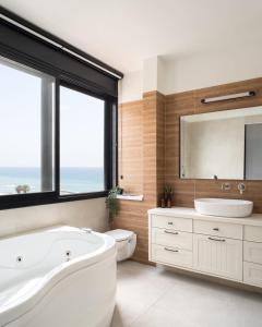 une salle de bain avec une baignoire, un lavabo et un miroir dans l'établissement שקיעה חלומית בנתניה, à Netanya