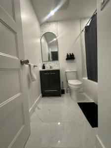 Un baño blanco con inodoro y espejo. en Luxury Sweet Home, en Longueuil 14 fotos más