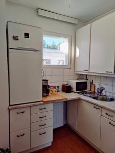 a kitchen with white cabinets and a white refrigerator at Costal Stay with Forest Views in Helsinki