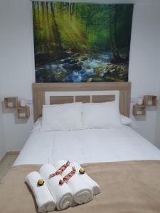a bed with two towels and a painting on the wall at Apartamento Rural Casa Mar in El Bosque