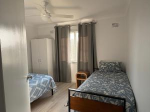 a small bedroom with a bed and a window at Caves Beach Holiday House in Caves Beach