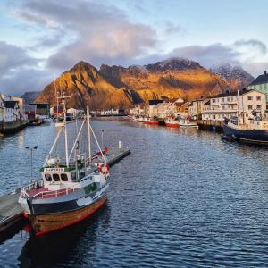 a boat is docked at a dock in a harbor at Seafront apartment Henningsvær in Henningsvær