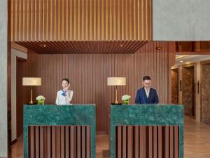 a man and woman standing behind two tables in a lobby at Mercure Nha Trang Beach in Nha Trang