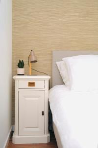 een wit nachtkastje naast een bed met een lamp erop bij Chalet met hottub in Putten