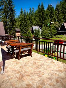 two wooden benches sitting on a patio next to a fence at Apartman RAJAN Vlašić in Vlasic +8 photos