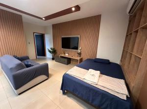a bedroom with a bed and a couch and a television at Rent Apartments Finch Nest in Puerto Baquerizo Moreno