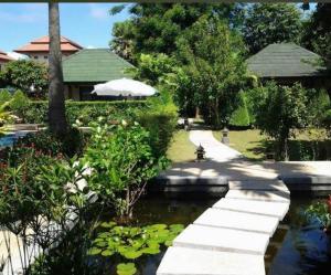 ein Gehweg über einen Teich in einem Garten in der Unterkunft Rawai Boutique Resort in Rawai Beach