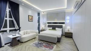 a bedroom with a bed and a couch and a chair at Le Aura Grand - Luxury Smart Hotel in Lahore by Urban Homes in Lahore