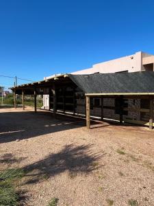 a wooden building with a black roof on a field at Santo Descanso in Punta Del Diablo