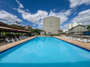 a swimming pool with lounge chairs and a building at Hotel Santiago in Lindóia