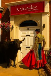 Ein Mann steht neben einem Stier vor einem Stadthaus in der Unterkunft The Mirador Boutique Town House in Swansea
