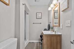 a white bathroom with a sink and a shower at Central Oshkosh Stay - Walk to Lake and Downtown in Oshkosh +26 photos