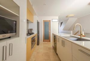 a kitchen with white cabinets and a sink at Upscale neighbourhood guest quarters in Perth +2 photos