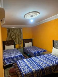 deux lits dans une chambre aux murs jaunes dans l'établissement La paillade, à Oulad Akkou