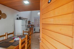 a door to a kitchen with a table and a refrigerator at BC Praia Estaleiro - 2 Vagas, Ar, Churras e Pet OK in Balneário Camboriú