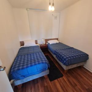 2 Betten in einem kleinen Zimmer mit Holzböden in der Unterkunft Departamento 3 dormitorios en villarica in Villarrica