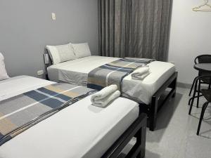 two beds in a hotel room with towels on them at Hostal Huella in Lambayeque +31 photos