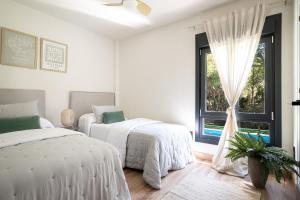 a white bedroom with two beds and a window at Chez Marie in La Muela