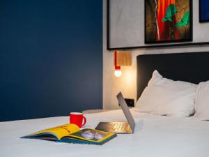 a bed with a book and a laptop on it at Ibis Styles Abidjan Plateau in Abidjan