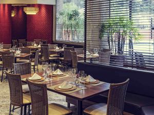 a restaurant with wooden tables and chairs and a window at Mercure Joinville Prinz in Joinville