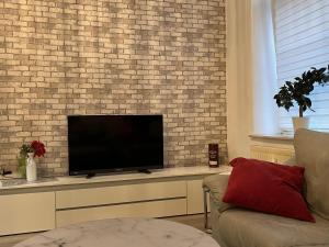 a living room with a flat screen tv on a brick wall at Seestadt Apartment in ruhiger Lage Erdgeschosswohnung mit WLAN in Bremerhaven +9 photos