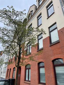 a red brick building with a tree in front of it at Seestadt Apartment in ruhiger Lage Erdgeschosswohnung mit WLAN in Bremerhaven