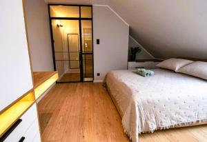 a bedroom with a white bed and wooden floors at Marina Ostróda III - widok na jezioro, podziemny garaż, winda, klimatyzacja, wanna i prysznic, 2 łazienki, lux in Ostróda +21 photos