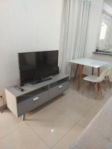 ein Wohnzimmer mit Fernseher und Tisch in der Unterkunft Apartamento novinho e aconchegante in Piracicaba