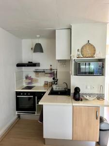 Una cocina con gabinetes blancos y un horno de estufa. en Studio avec terrasse - Accès plage et piscine, en Îlet à Boissard