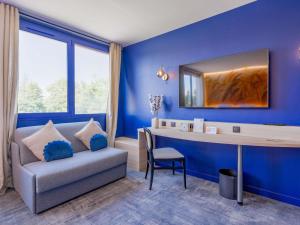 a blue room with a couch and a desk at Mercure Lyon Est Villefontaine in Villefontaine