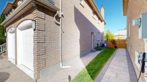 a brick building with a white door and a driveway at Home Away From Home in Richmond Hill