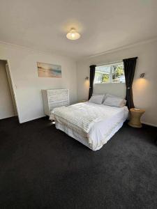 un dormitorio con una cama y una ventana en Ohope Ocean Breeze Escape, en Ohope Beach