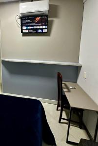 a room with a table and a television on the wall at Loft Lux SM 07 (Smart TV, Ar condicionado, Cozinha) in Chapecó