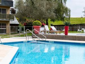a swimming pool in a yard with chairs and a house at Mercure Bayeux Omaha Beach in Port-en-Bessin-Huppain