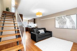 a living room with a black couch and a staircase at Wagga Central Apartments in Wagga Wagga +9 photos