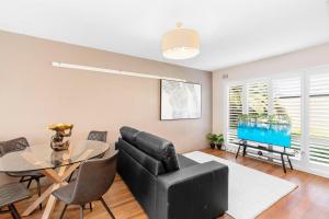 a living room with a glass table and a black couch at Wagga Central Apartments in Wagga Wagga