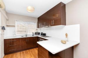 a kitchen with wooden cabinets and a white counter top at Wagga Central Apartments in Wagga Wagga