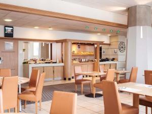 a restaurant with tables and chairs and a counter at Mercure Rennes Centre Gare in Rennes
