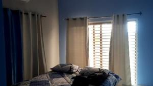 Un dormitorio con una cama con almohadas y una ventana. en Ponta Family holiday house, en Ponta do Ouro