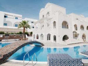 a large white building with a swimming pool at my life suites in Fira +49 photos