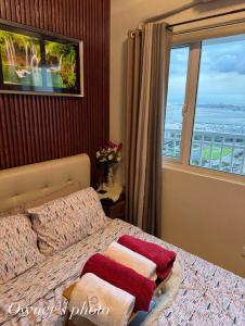ein Schlafzimmer mit einem Bett mit zwei Kissen und einem Fenster in der Unterkunft Juvrey Studio-Unit Breeze Residences in Manila