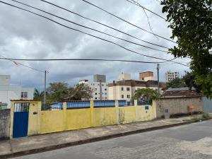 a yellow fence on the side of a street with buildings at Casa Geminada in Contagem