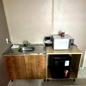a small kitchen with a sink and a microwave at Loft Lux 2 (Smart TV, Ar condicionado, Cozinha...) in Chapecó +5 photos