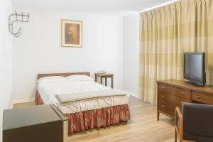 a small bedroom with a bed and a tv at Economy Inn in Temple