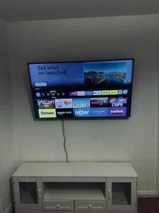 ein Flachbildfernseher, der an einer Wand hängt in der Unterkunft Stylish Wembley Home with Hot Tub, Parking & Garden in London