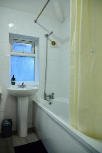 ein weißes Badezimmer mit einem Waschbecken, einer Badewanne und einem Waschbecken in der Unterkunft Stylish Wembley Home with Hot Tub, Parking & Garden in London + 21 Fotos