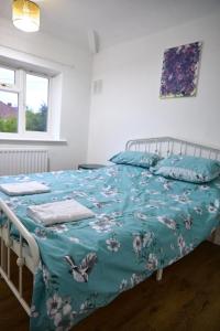 ein Schlafzimmer mit einem Bett mit einer blauen Decke in der Unterkunft Stylish Wembley Home with Hot Tub, Parking & Garden in London