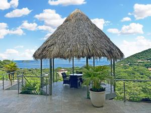 a patio with a table and a straw umbrella at Modern 4 Bedroom Infinity Pool Beach, Sunset, in Playa Hermosa