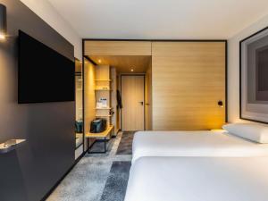 a bedroom with a large bed and a flat screen tv at ibis Nancy Centre Stanislas in Nancy