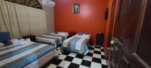 a room with two beds and a checkered floor at Hotel Rancho Infinito in El Cuco